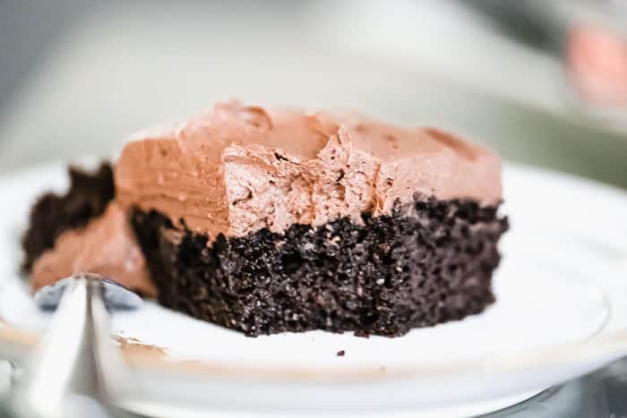Easy Keto Chocolate Cake sitting on a white plate with one bite taken out of the corner of the cake