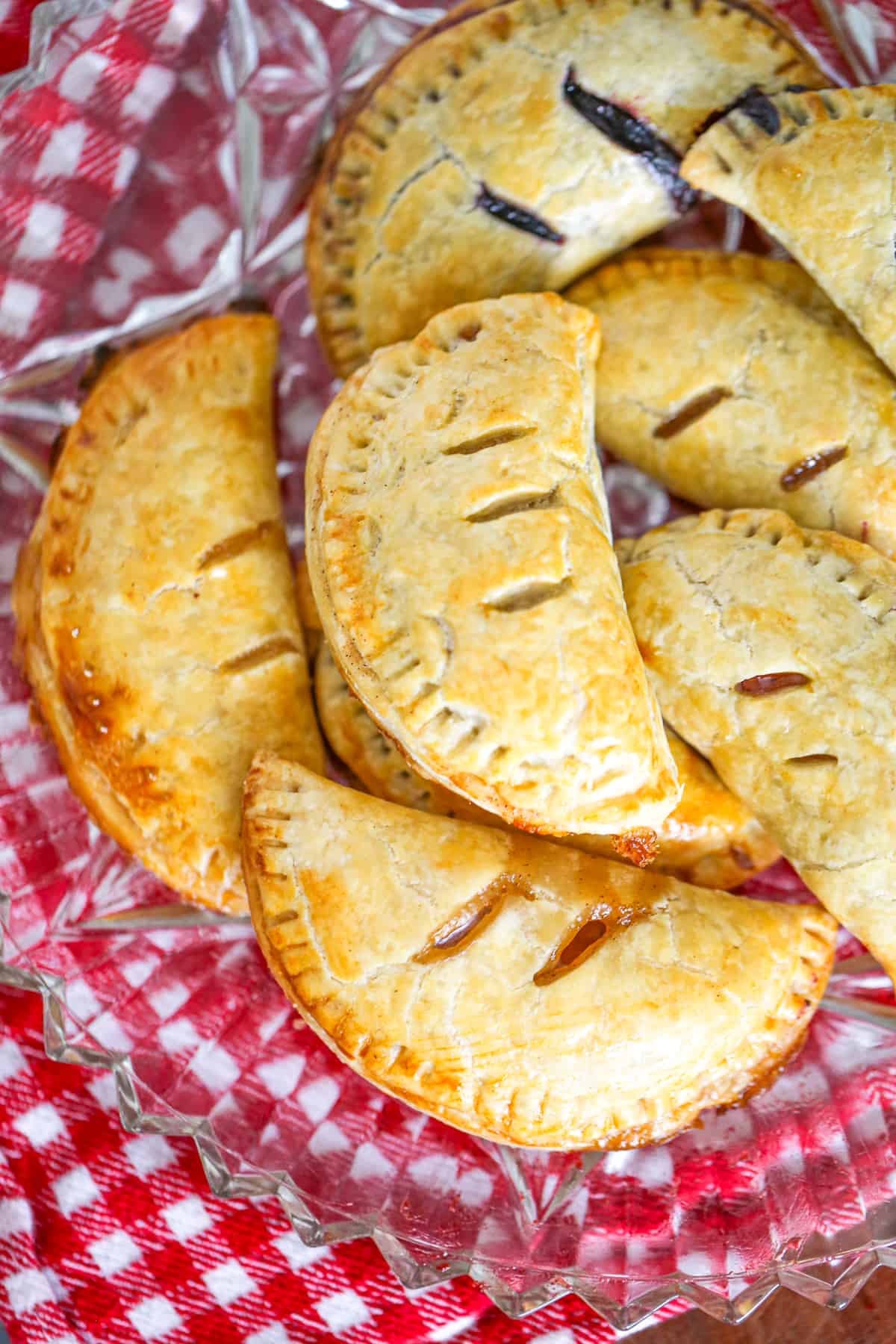 easy hand held pies recipe with shortcuts apple, blueberry, cherry, peach, blueberry, raspberry fillings using pie crust and topped with glaze