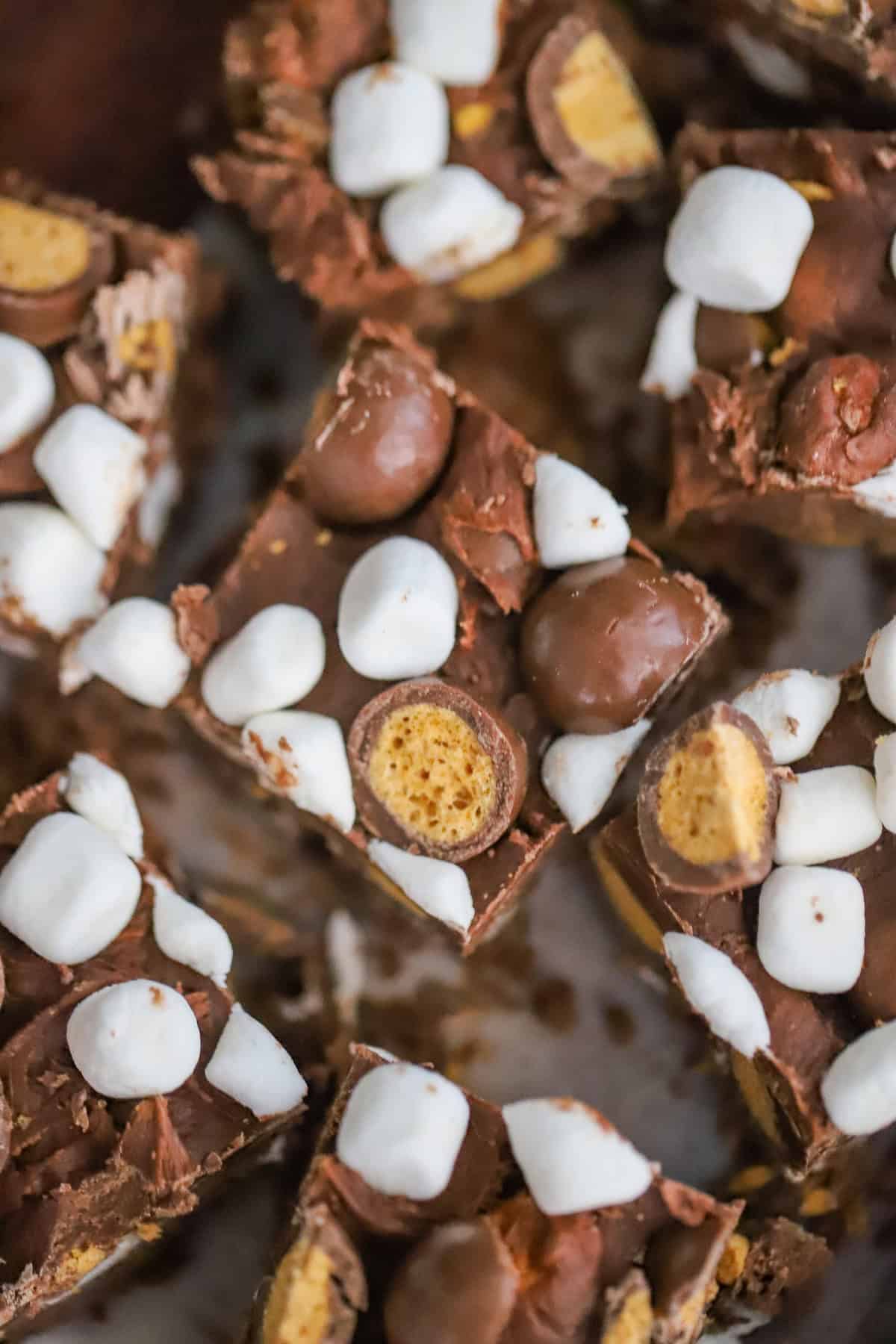 Chocolate chips, frosting, Whoppers, and mini marshmallows on counter