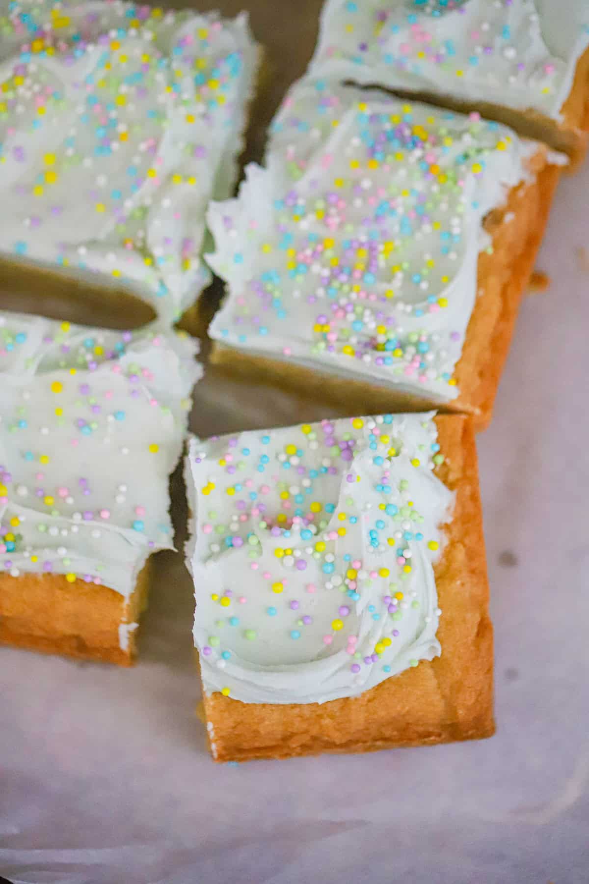 Close-up of thick chewy spring cookie bar with green frosting and sprinkles