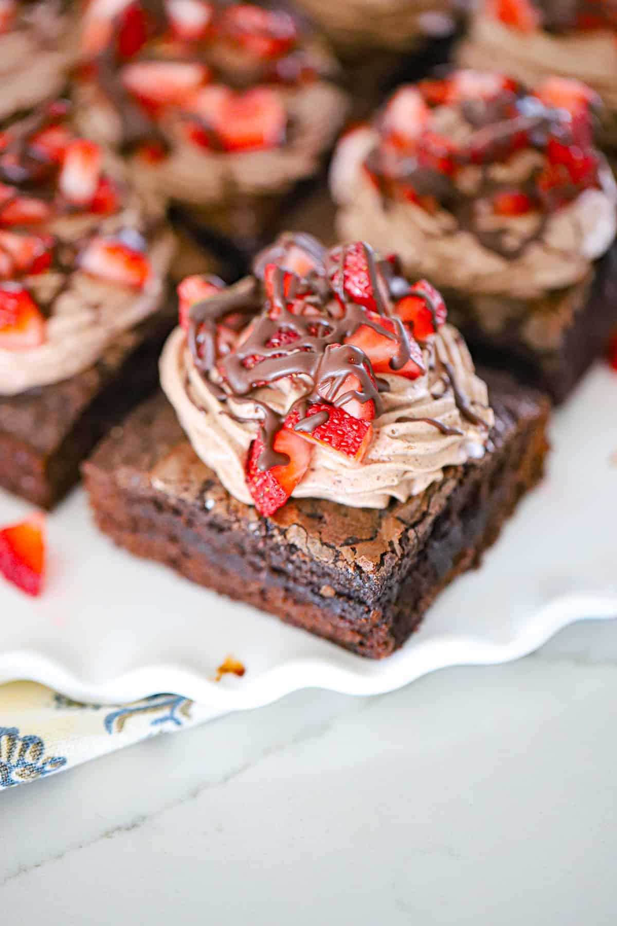 Chocolate whipped cream brownies topped with fresh strawberries and chocolate drizzle