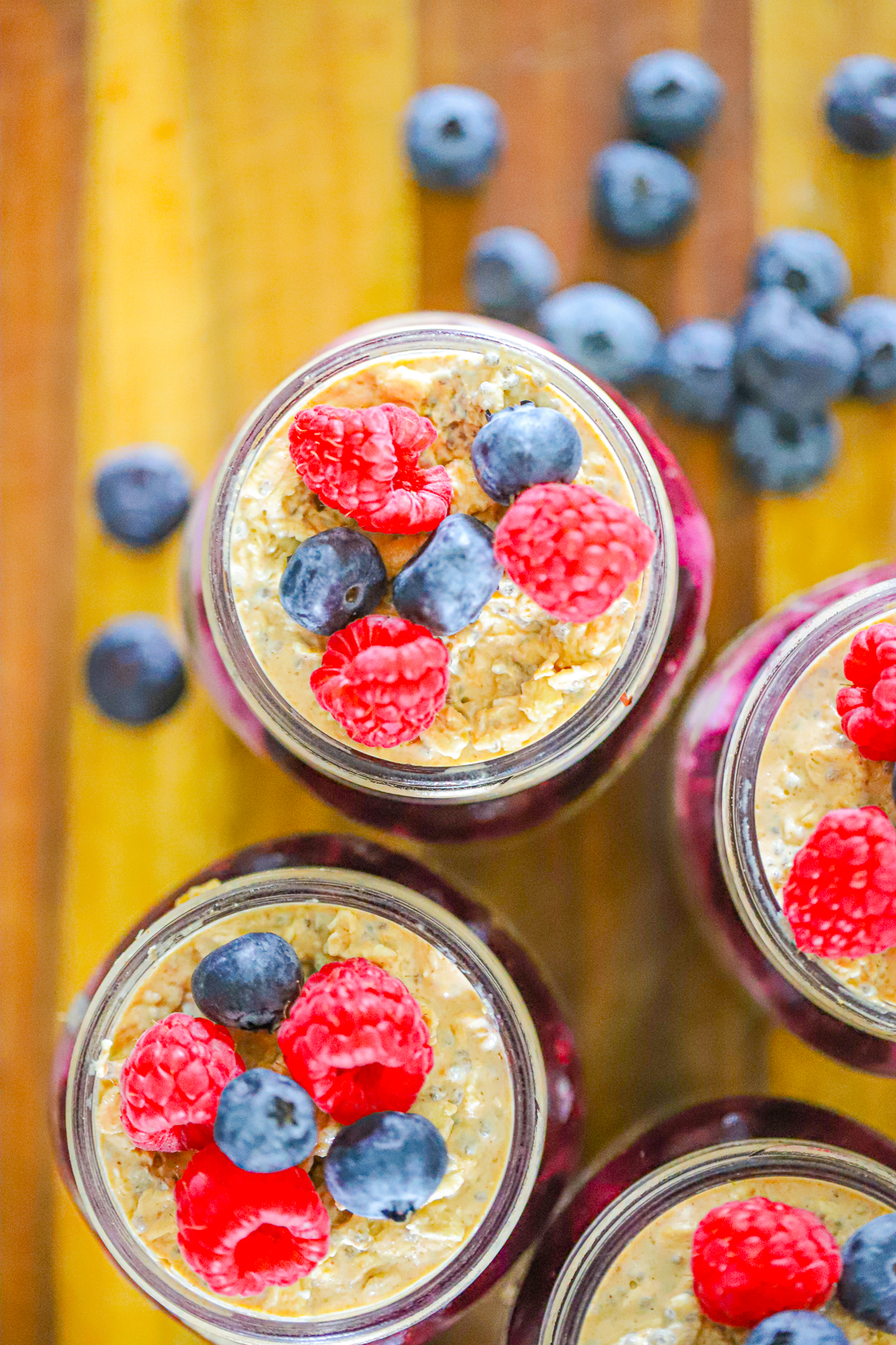 Thick creamy oats topped with fresh blueberries and raspberries in a tall glass jar