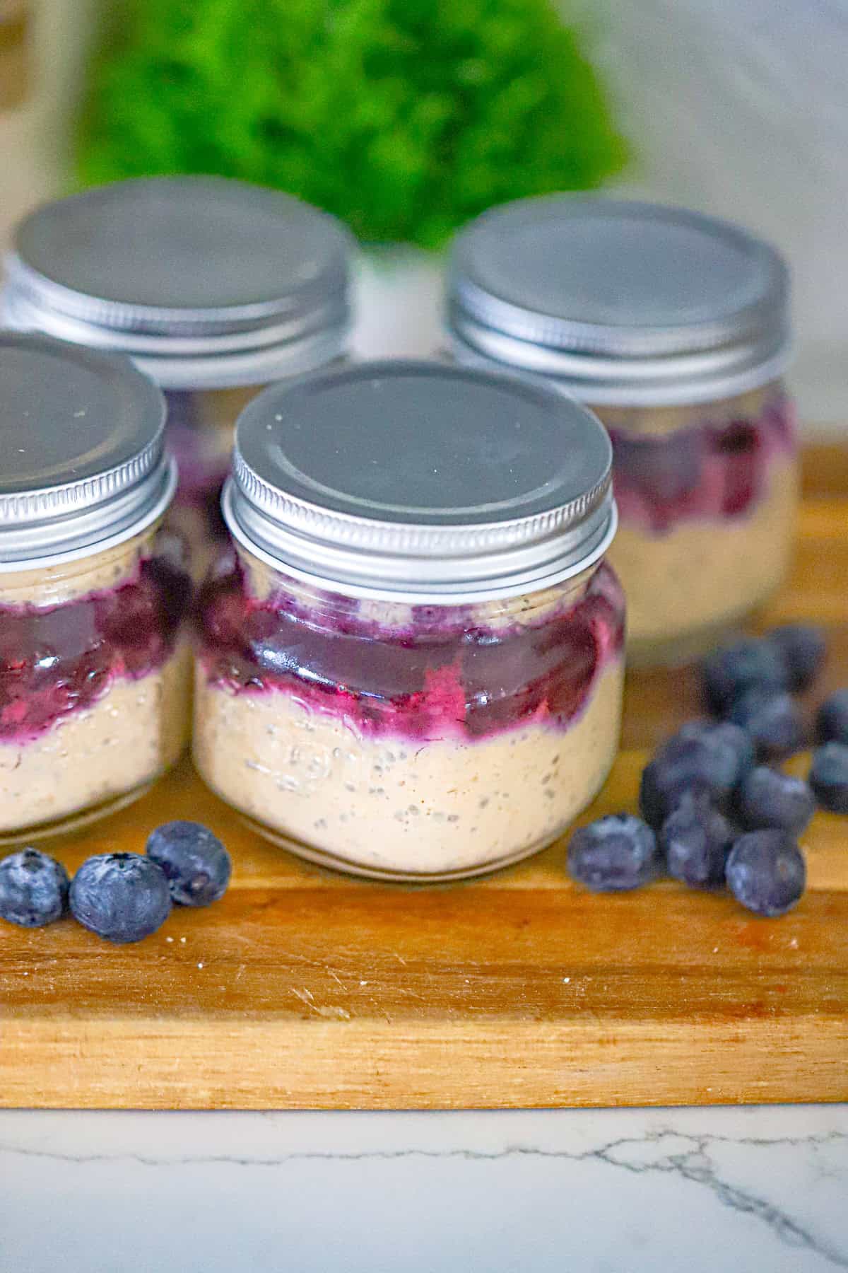 Tall glass jar of creamy oats topped with fresh berries and a jammy swirl