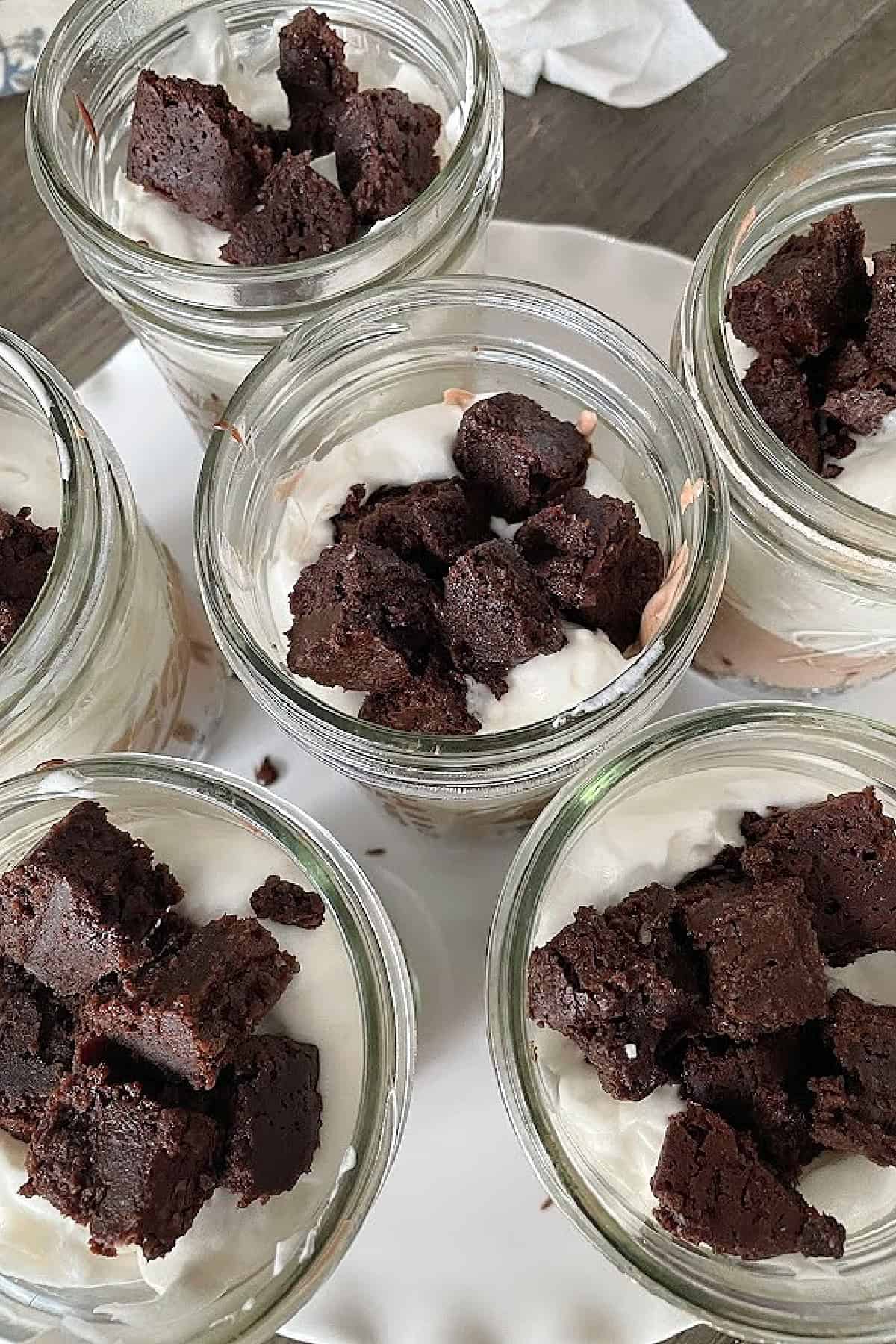 Brownie cubes and chocolate mousse layered into clear cups for brownie parfaits