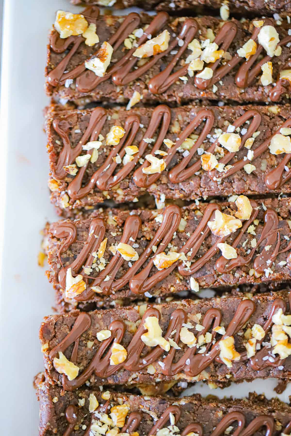 Close up of chocolate brownie bar showing fudgy date texture and walnut pieces