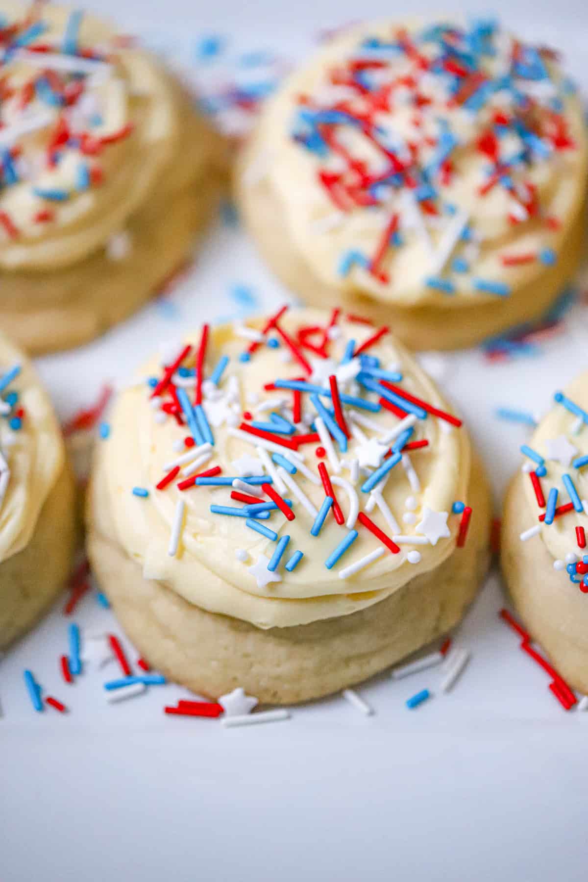 Soft buttery sugar cookie topped with swirled vanilla buttercream frosting red white and blue cookies