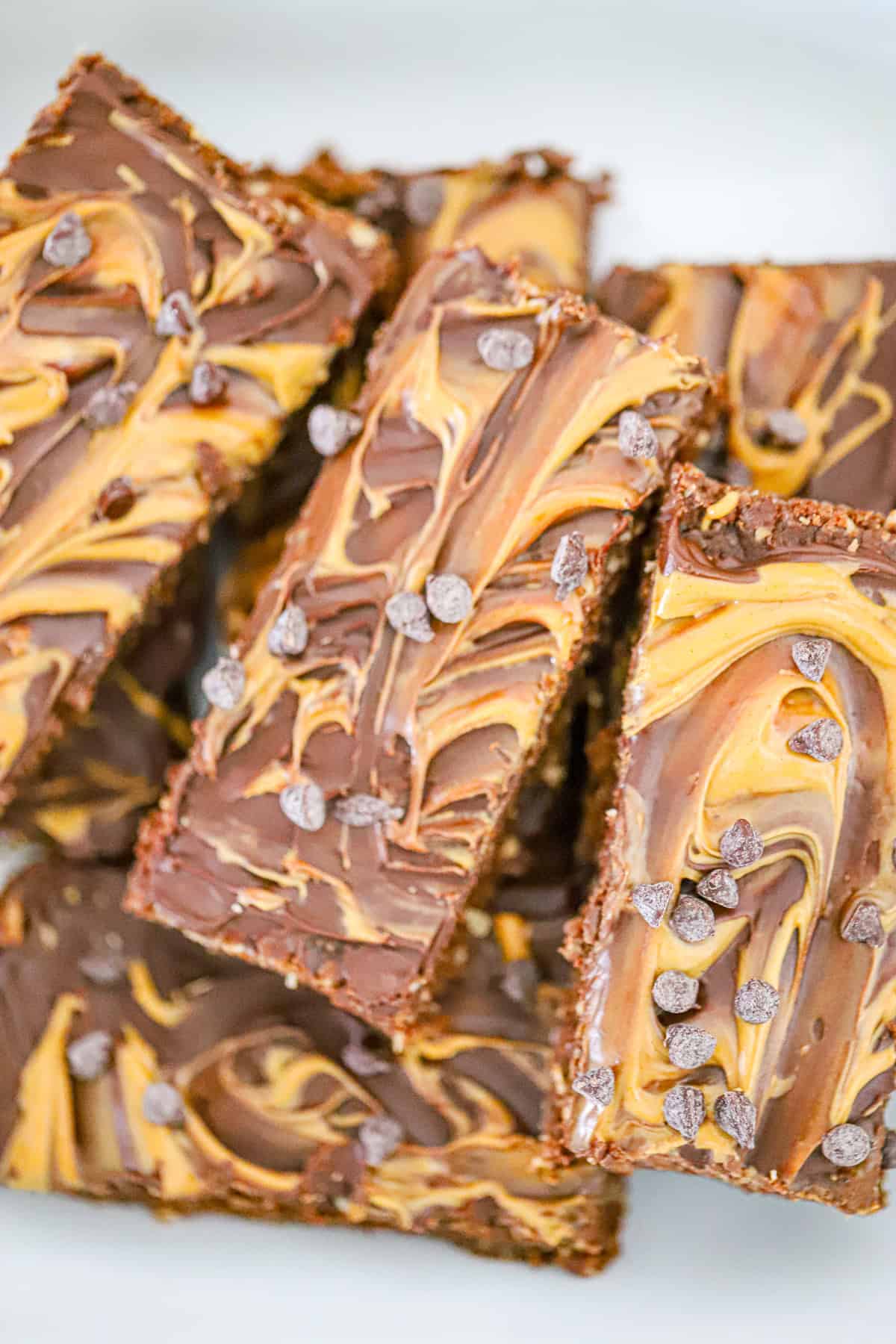 Peanut butter caramel brownie protein bars stacked and sliced on parchment paper
