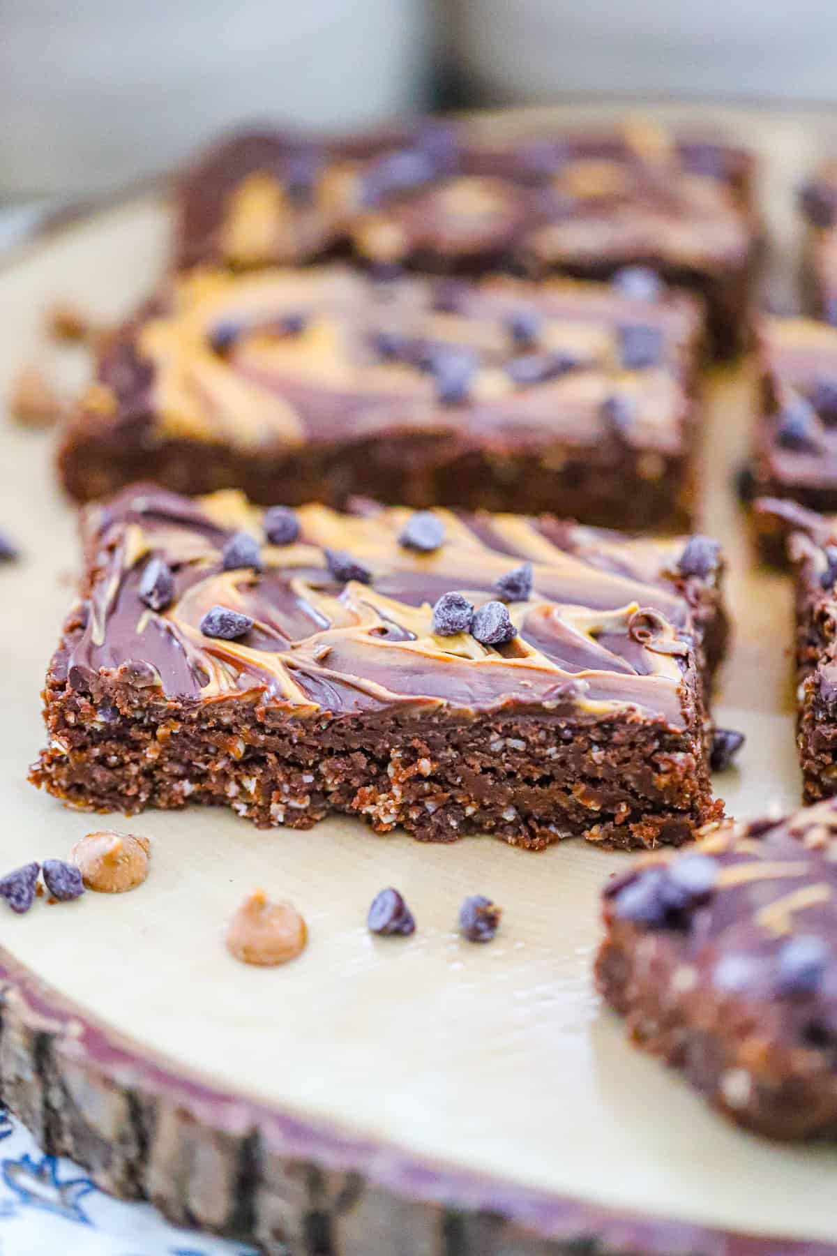 Stack of fudgy caramel brownie protein bars topped with chocolate chips