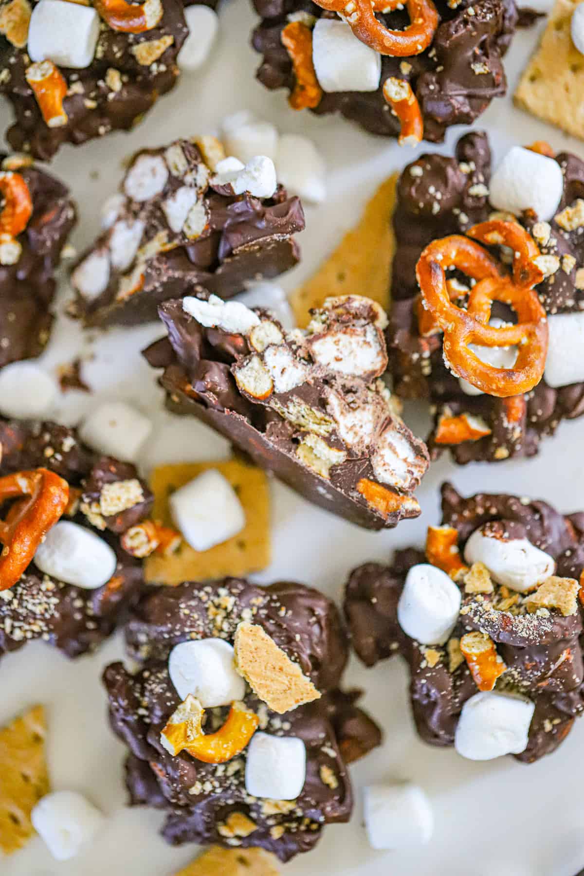 Broken pretzels, mini marshmallows, graham cracker chunks, and chocolate chips in bowls