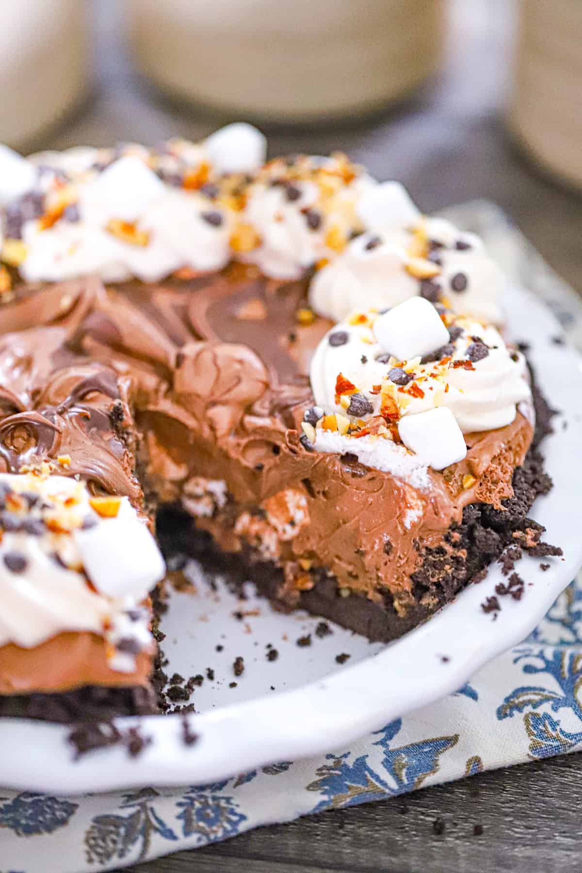 Slice of chocolate marshmallow pie on a plate with hershey frosting drizzle dessert no bake rocky road pie