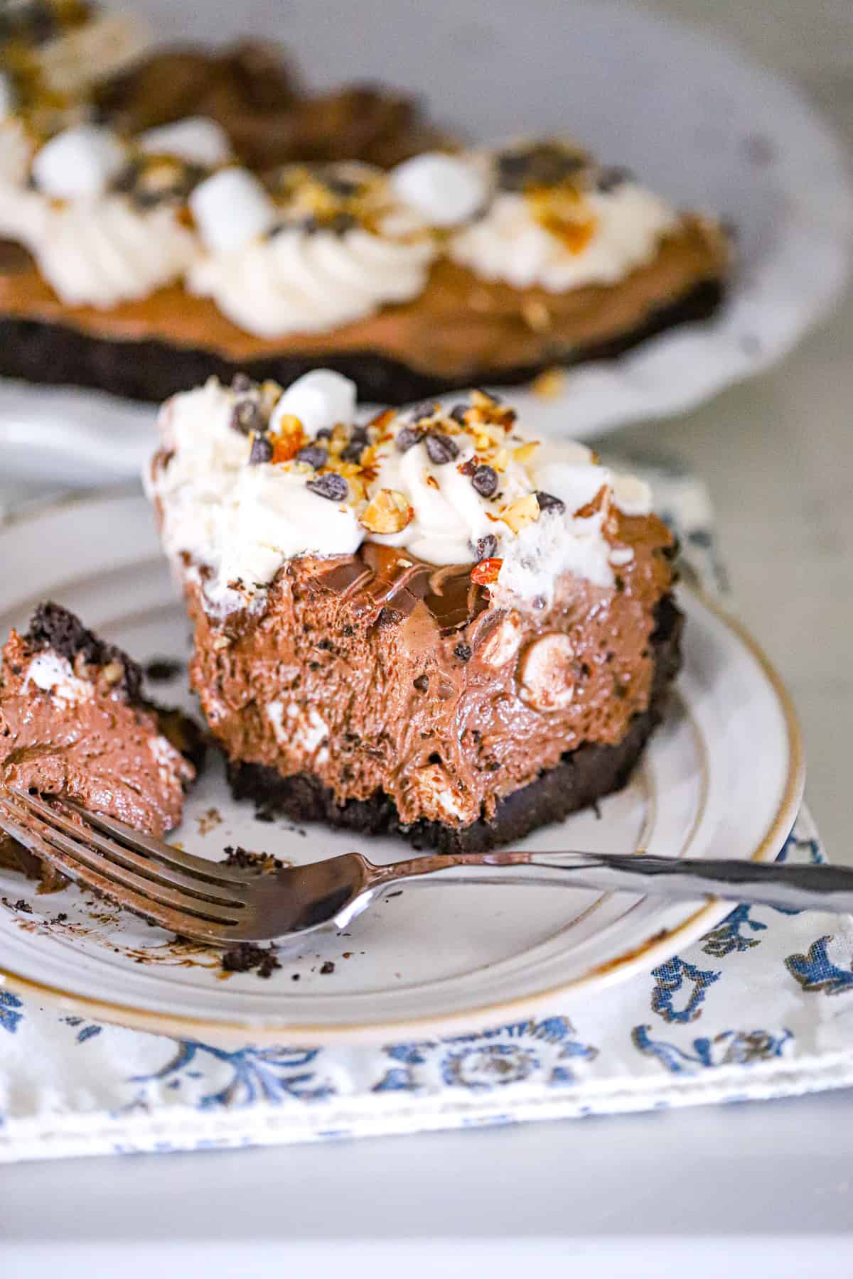 Tall slice of no bake rocky road pie with whipped cream rosettes and chocolate drizzle hershey dessert