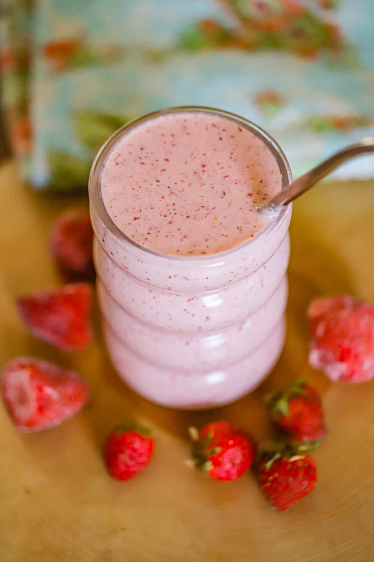 frosty pink smoothie poured into a clear glass with fresh fruit