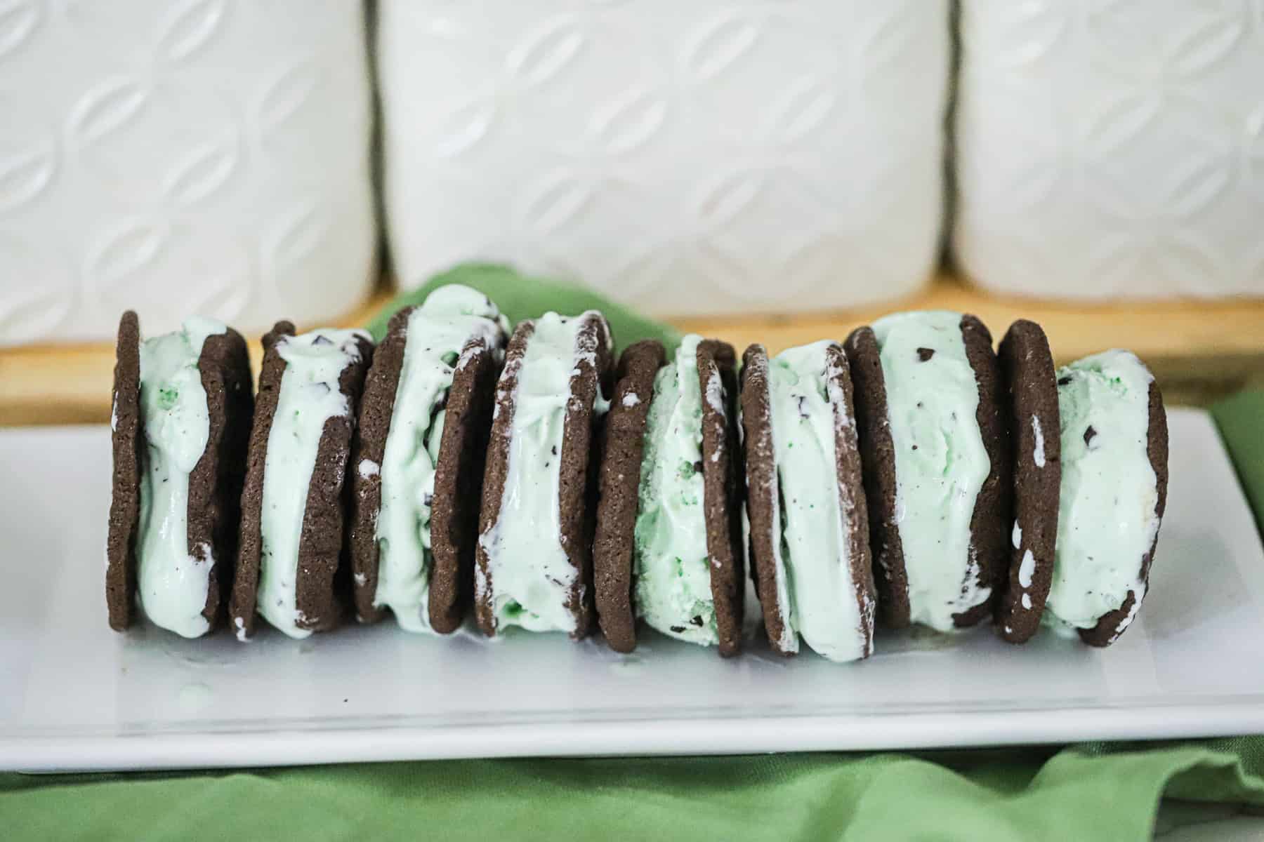 Thin and chewy brownie‑thin cookies filled with mint chip ice cream, stacked as homemade ice cream bars.