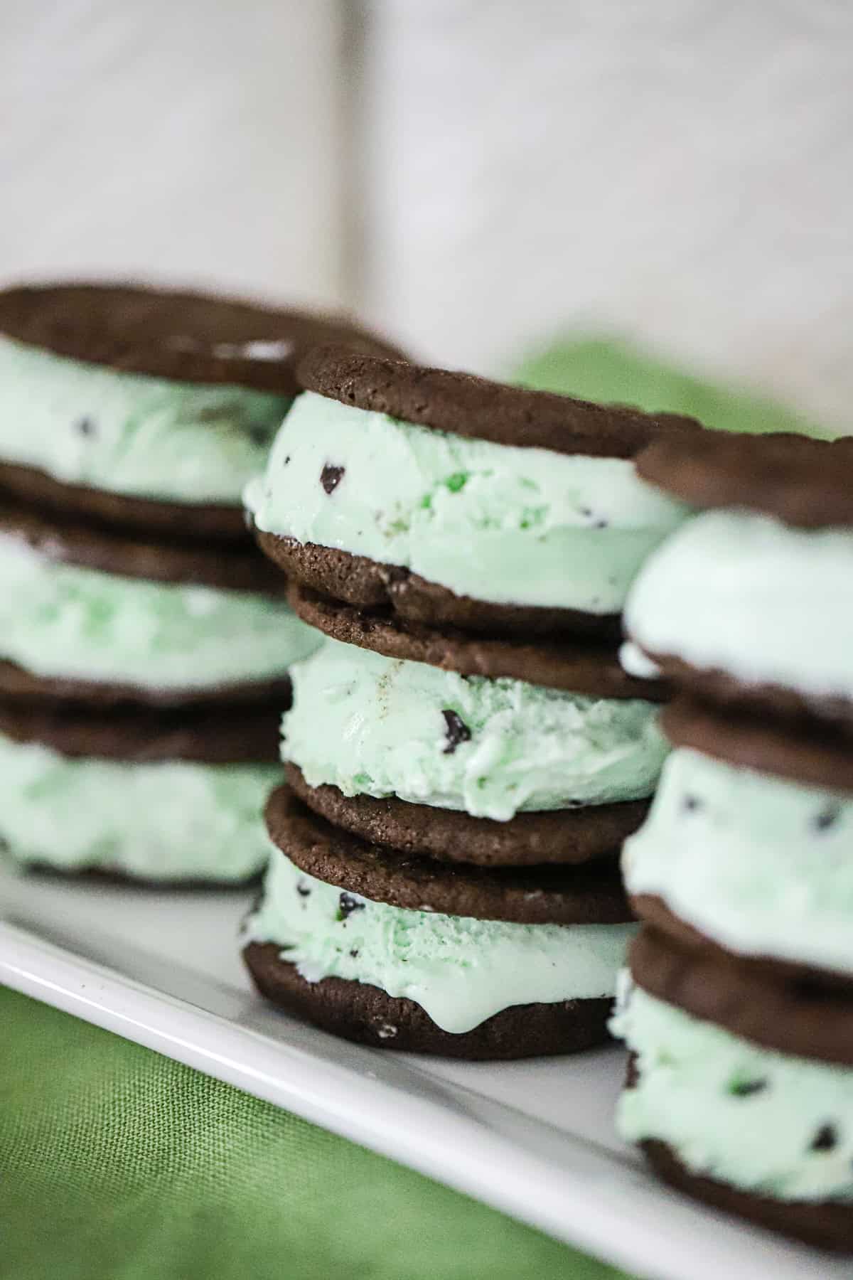 Thin and chewy brownie‑thin cookies filled with mint chip ice cream, stacked as homemade ice cream bars.
