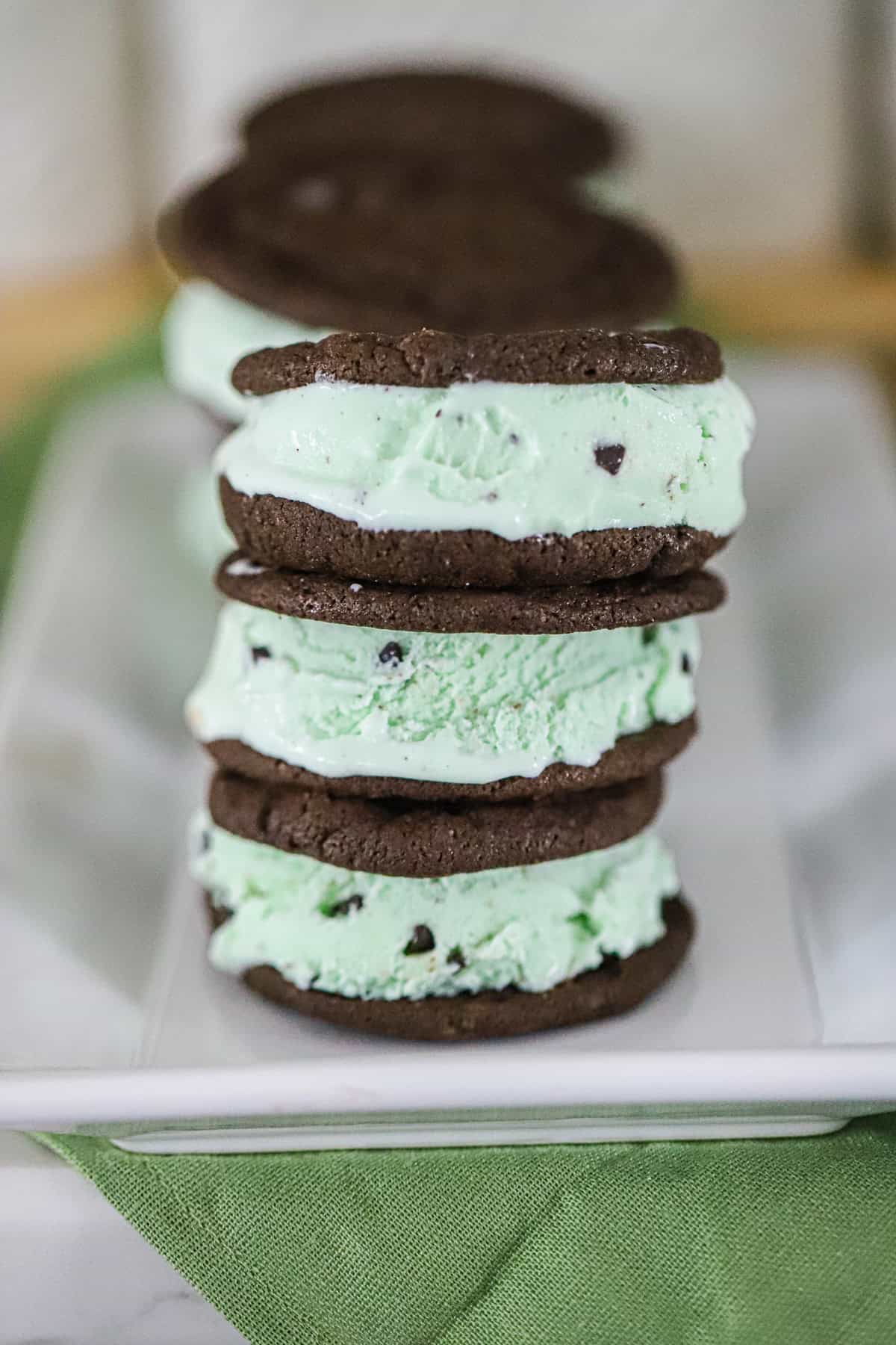 stack of Homemade brownie‑thin cookie ice cream bars with mint chip filling on a platter.
