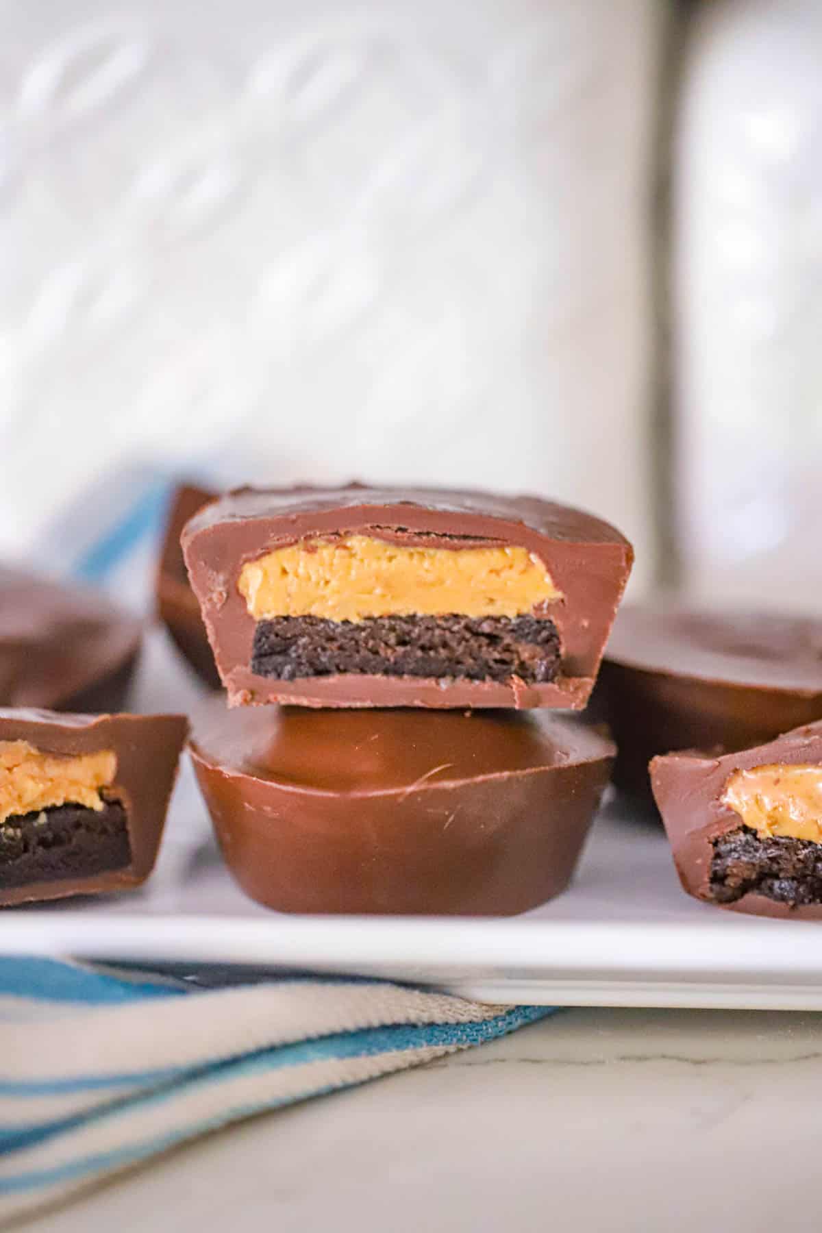 Melted chocolate poured over brownie and peanut butter layers in silicone cups