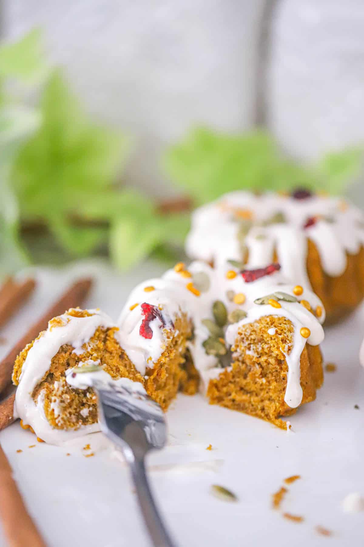 Cream cheese drizzle flowing over individual spiced cakes