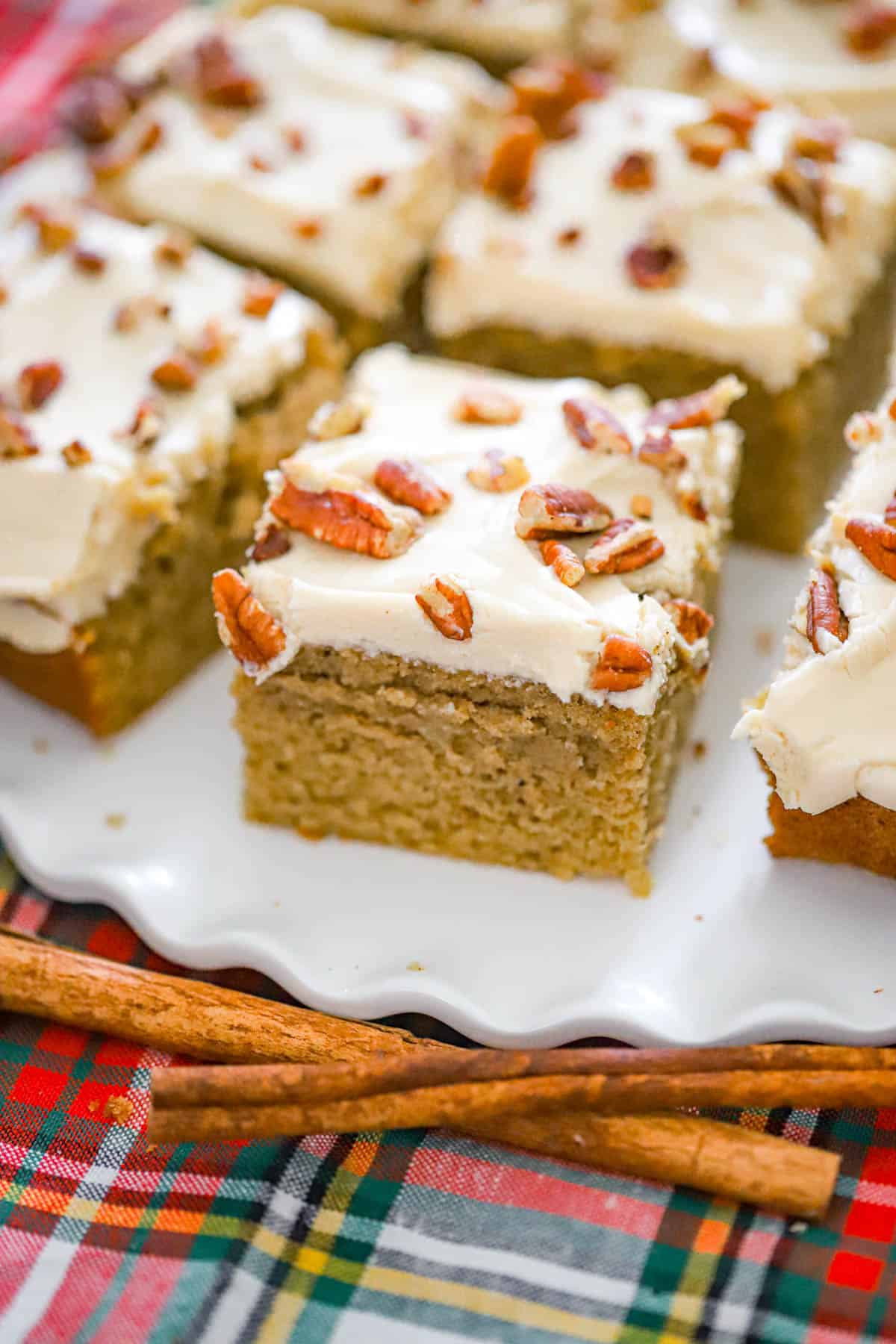 Chai spice cake square showing its tender crumb, creamy frosting, and pecan topping - fall snack cake recipe